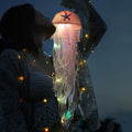 Jellyfish Lamp - Side view of an illuminated orange jellyfish, elegantly held by a woman.